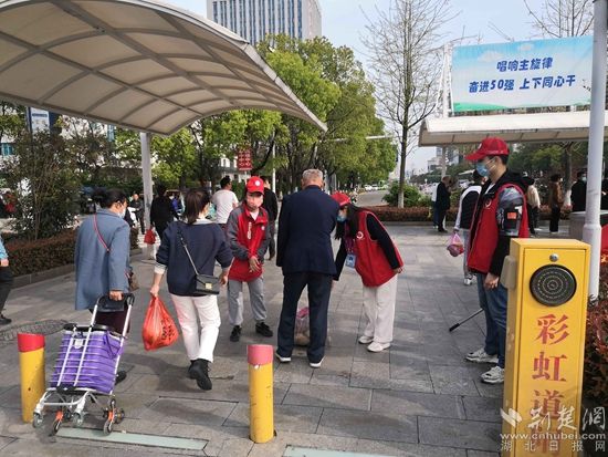 志愿服务队在人民医院路口开展文明交通体验活动，并帮助老人提重物.jpg.jpg