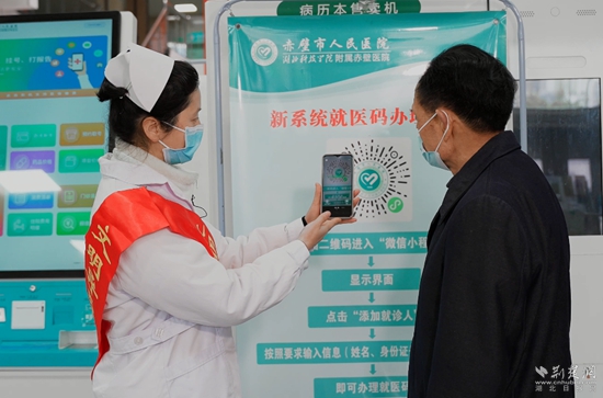 导诊员指导患者扫就医码“一码通”（摄影：陈影）.jpg
