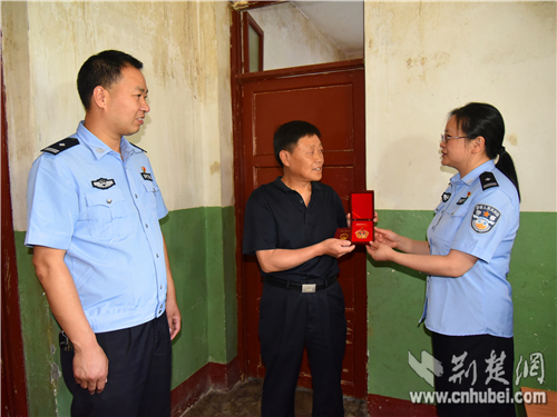 图为十堰市公安局郧阳区分局党委委员、政工室主任兰海燕（右）为退休民警杨善龙颁发人民警察光荣退休纪念勋章。 通讯员 张君 摄_副本.jpg