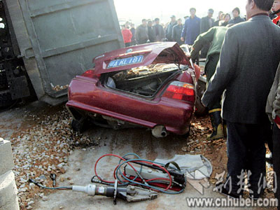 满载沙石翻斗车压趴小轿车 众手刨开沙石救回