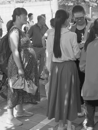 在武汉一中考点前,已怀孕9个多月的闵女士挺着大肚子,来给女儿送考