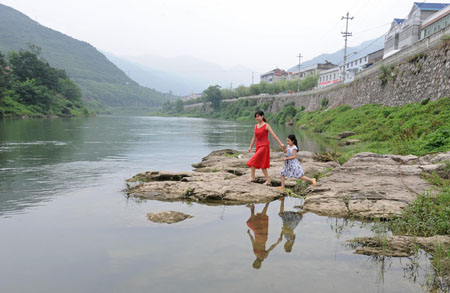 一位镇上居民带着小孩在河边玩耍.