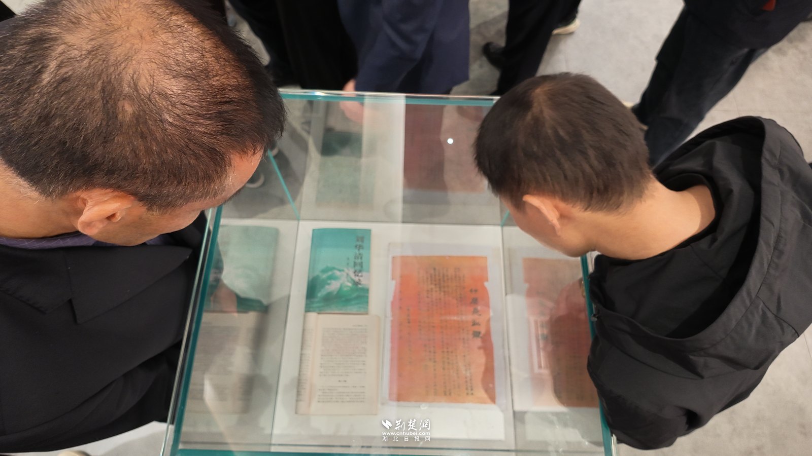 参观者俯身细看展柜里的《什么是红军》传单。
