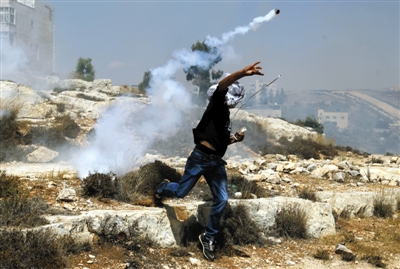 2日,巴勒斯坦约旦河西岸,一名巴勒斯坦人将以色列军队发射的催泪瓦斯